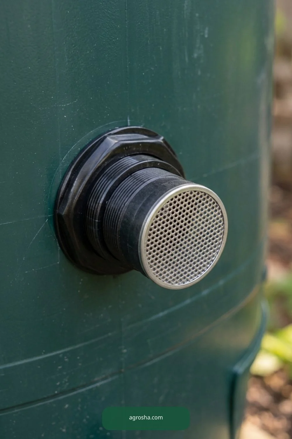 Close-up of small round insect mesh covering threaded rain barrel overflow opening
