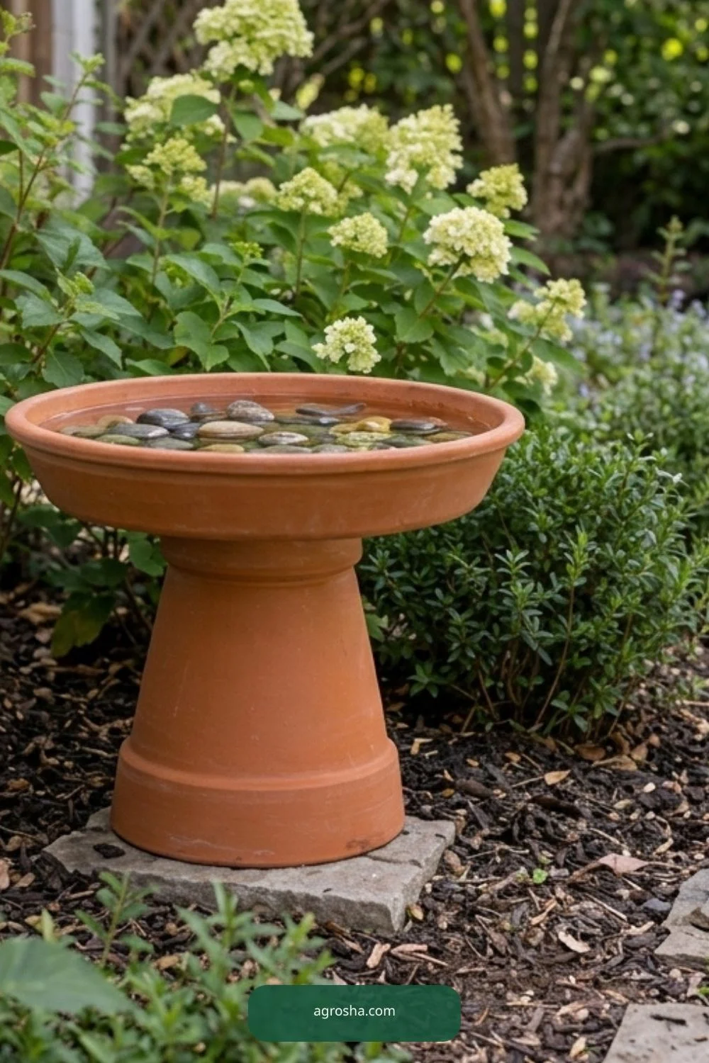 Completed DIY terracotta pot bird bath with shallow water and stones in a modest backyard garden